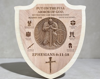 May include: Wooden shield with a light wood border and a central design. The shield features a detailed engraving of a knight, surrounded by text and symbols. The text reads "PUT ON THE FULL ARMOR OF GOD, EPHESIANS 6:11-18".
