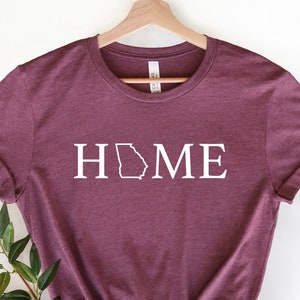 May include: A maroon t-shirt with the word "HOME" in white text, with the outline of the state of Georgia replacing the "O".