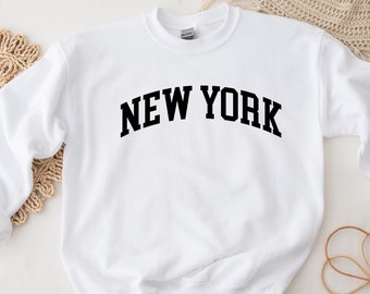 May include: White sweatshirt with black text that reads "NEW YORK" in an arched font.