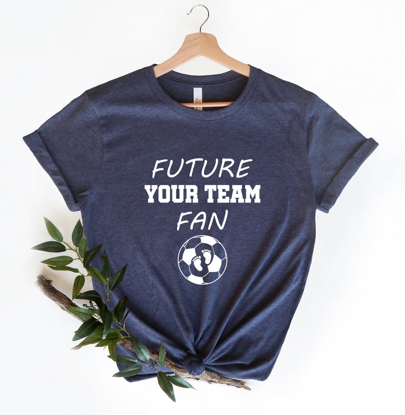 May include: A navy blue t-shirt with white text that reads "Future Your Team Fan" and a soccer ball with footprints inside.