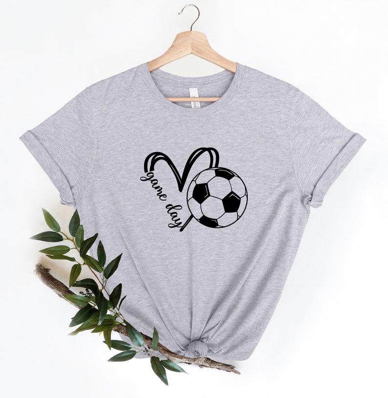 May include: Gray t-shirt with a black and white soccer ball graphic and the text "game day" in a heart shape.