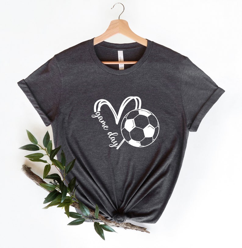 May include: A dark gray t-shirt with a white soccer ball and the words "game day" in a heart shape.