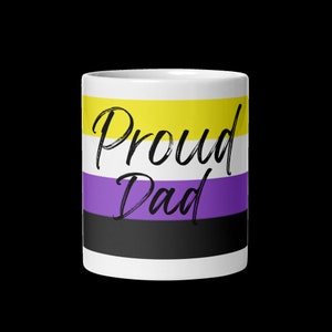 May include: White ceramic mug with a yellow, purple, and black striped design. The text "Proud Dad" is written in black on the mug.
