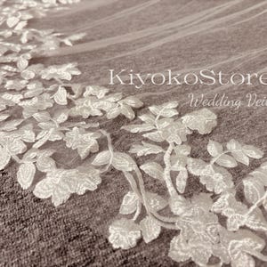 May include: White wedding veil with delicate floral embroidery. The veil is made of soft tulle and features a delicate floral pattern. The veil is perfect for a bride who wants a classic and elegant look.