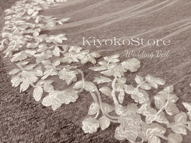 May include: White wedding veil with delicate floral embroidery. The veil is made of soft tulle and features a delicate floral pattern. The veil is perfect for a bride who wants a classic and elegant look.