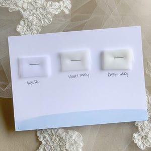 May include: A white card with three fabric swatches labeled "White", "Light Ivory", and "Dark Ivory".