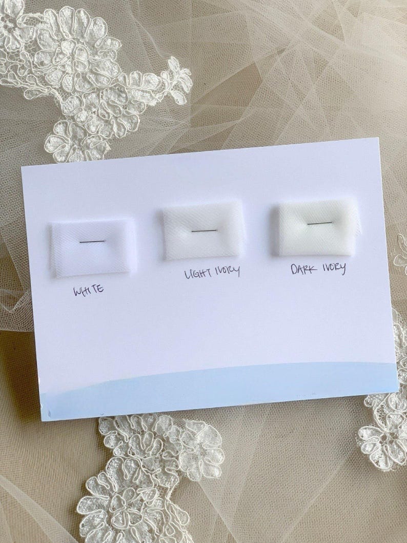 May include: A white card with three fabric swatches labeled "White", "Light Ivory", and "Dark Ivory".