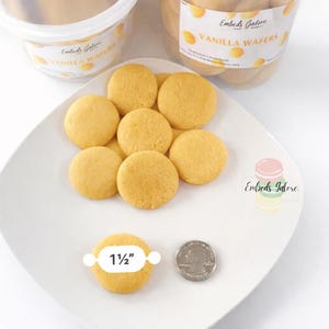 Vanilla wafer–shaped soy wax embeds arranged on a white plate with a 1½-inch size reference and U.S. quarter for scale, shown in front of labeled Vanilla Wafers containers on a clean white background.