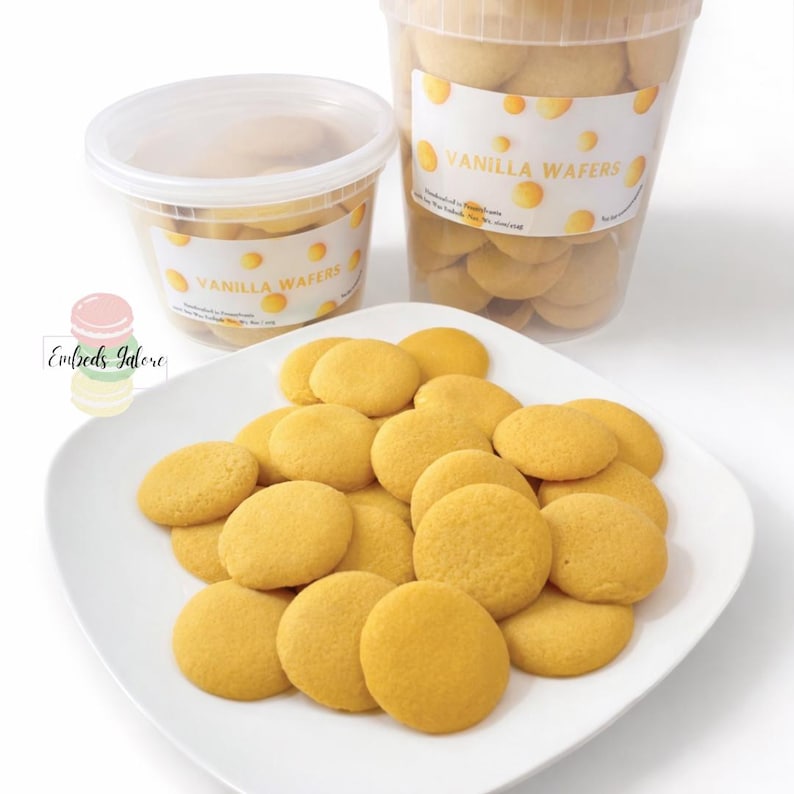 Vanilla wafer–shaped soy wax embeds displayed on a white plate, with two clear containers labeled ‘Vanilla Wafers’ in the background on a clean white surface.