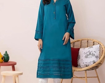 May include: A teal blue long-sleeved tunic with lace detailing on the sleeves and hem. The tunic is paired with white pants that also have lace detailing.