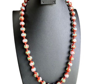 May include: A red and white floral patterned beaded necklace. The beads are round and have a glossy finish.