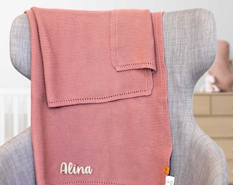 May include: A soft pink knitted baby blanket with the name "Alina" embroidered on it.