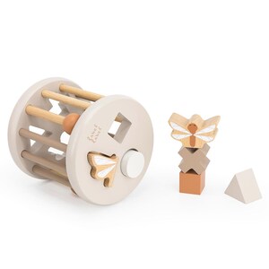 May include: A wooden toy with a rolling cylinder and a shape sorter. The cylinder has a wooden ball inside and the shape sorter has a square, circle, and butterfly shapes. The toy is made by L&Auml;SSIG.