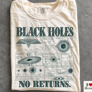 Peut inclure: Un t-shirt ivoire avec du texte vert foncé et des diagrammes scientifiques sur les trous noirs. Le graphique inclut les équations d'Einstein, le rayon de Schwarzschild, des disques d'accrétion et le texte Black Holes No Returns.