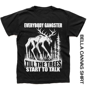 Op de afbeelding: Zwart Bella Canvas shirt met een witte afbeelding van een wezen met geweien en de tekst "EVERYBODY GANGSTER TILL THE TREES START TO TALK". Het shirt heeft ook de tekst "BELLA CANVAS SHIRT" aan de zijkant.