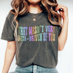 Könnte beinhalten: Ein graues T-Shirt mit dem Text "That wasn't very data-driven of you" in Regenbogenfarben.
