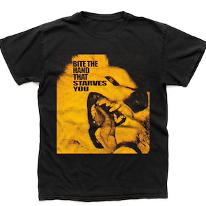 May include: Black t-shirt featuring a yellow graphic of a snarling dog's face. The text "BITE THE HAND THAT STARVES YOU" is printed in white above the dog's face. The shirt is made of a soft material.