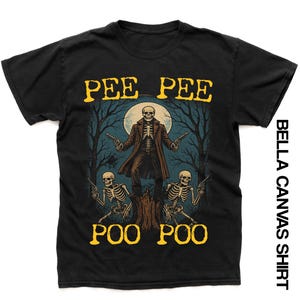 May include: Black Bella Canvas shirt with a skeleton cowboy graphic holding two guns, set against a moonlit forest backdrop. The shirt displays the words "PEE PEE" and "POO POO" in yellow, with "BELLA CANVAS SHIRT" on the side.