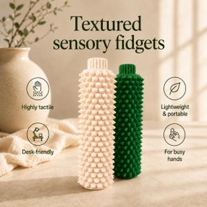May include: Two cylindrical sensory fidgets, one beige and one dark green, featuring a uniform spiky, textured surface. The text "Textured sensory fidgets" appears above, with icons and labels "Highly tactile," "Lightweight & portable," "Desk-friendly," and "For busy hands" surrounding the objects.