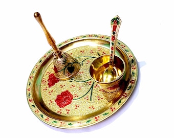 Puede incluir: Un plato de metal dorado con un diseño decorativo de flores rojas y hojas verdes. El plato incluye una pequeña campana, un tazón y una cuchara, todos hechos del mismo metal.