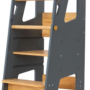 May include: A grey and natural wood learning tower with multiple levels. The tower has a sturdy frame with a grey finish and natural wood steps and rails. It features a step-up design for children.