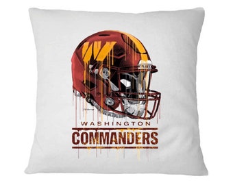 May include: A white pillow with a red and gold football helmet with a dripping paint effect. The helmet has a "W" on the side. The text "WASHINGTON COMMANDERS" is below the helmet.
