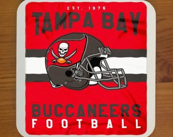 May include: A square coaster in red, white and black with the words "Tampa Bay Buccaneers Football" and the team logo, a skull and crossbones with a football, inside a football helmet.