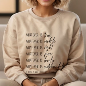 K&ouml;nnte beinhalten: Ein beiger Pullover mit dem Aufdruck "WHATEVER IS true WHATEVER IS noble WHATEVER IS right WHATEVER IS pure WHATEVER IS lovely WHATEVER IS admirable IF THERE IS ANY EXCELLENCE, IF THERE IS" auf der Vorderseite.