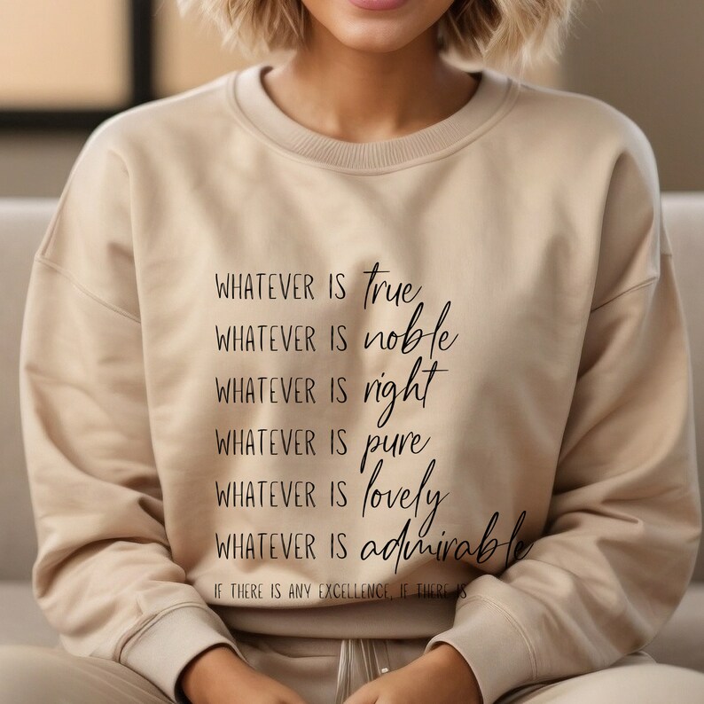 K&ouml;nnte beinhalten: Ein beiger Pullover mit dem Aufdruck "WHATEVER IS true WHATEVER IS noble WHATEVER IS right WHATEVER IS pure WHATEVER IS lovely WHATEVER IS admirable IF THERE IS ANY EXCELLENCE, IF THERE IS" auf der Vorderseite.