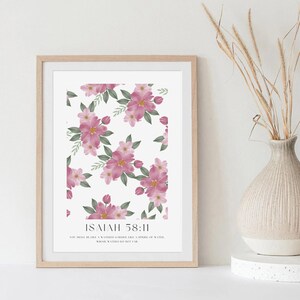 Puede incluir: Un diseño de arte de pared imprimible con un patrón floral con flores rosas y hojas verdes. El texto "ISAIAH 58:11" está impreso debajo del patrón floral. El texto debajo del versículo dice "Serás como un huerto regado, como un manantial de agua, cuyas aguas no se agotan."