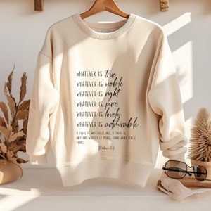 K&ouml;nnte beinhalten: Ein beiger Pullover mit einem schwarzen Aufdruck, der lautet: "WHATEVER IS true WHATEVER IS noble WHATEVER IS right WHATEVER IS pure WHATEVER IS lovely WHATEVER IS admirable IF THERE IS ANY EXCELLENCE, IF THERE IS ANYTHING WORTHY OF PRAISE, THINK ABOUT THESE THINGS Philippians 4:8"
