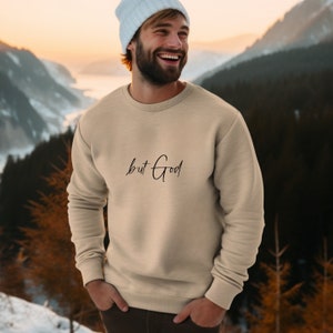 Pu&ograve; includere: Una felpa beige con la scritta "but God" in corsivo nero.
