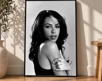 Puede incluir: Un retrato en blanco y negro en un marco negro fino que muestra a una persona con cabello oscuro largo mirando por encima del hombro. La persona viste una prenda superior oscura y un anillo en el dedo, en un estilo monocromático de alto contraste.
