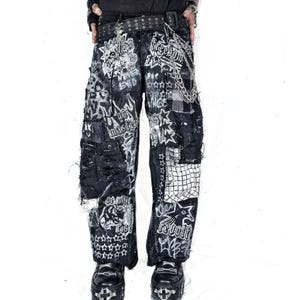 May include: Black denim pants with distressed patches and white graphic designs. The pants feature multiple patches, chains, and a studded belt. The designs include stars, skulls, and text. The pants are worn with black platform shoes.