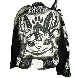 May include: Black and green jacket with a white graphic print of a rabbit with a flower and a paw print. The jacket has a fur collar and the text "Eternal Vortex" on the back.