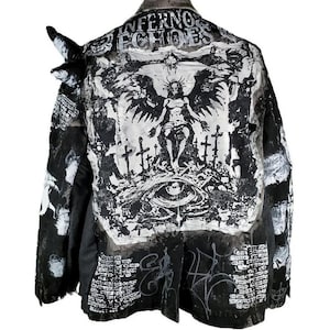 May include: Black and white jacket with a distressed look. The jacket features a large graphic print of an angel with wings and a halo, surrounded by crosses. The text "Infernos Echoes" is printed on the back of the jacket.