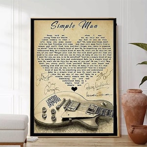 Può includere: Una stampa in stile vintage di un foglio di parole di una canzone con uno sfondo marrone sbiadito. Le parole sono per la canzone "Simple Man" di Lynyrd Skynyrd. La stampa presenta una chitarra elettrica in bianco e nero con una forma di cuore al centro. La stampa è firmata dai membri della band.