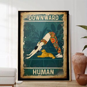 Könnte beinhalten: Ein Vintage-Poster mit einer Frau, die eine Yoga-Pose im Herabschauenden Hund macht, mit einem Hund an ihrer Seite. Das Poster trägt den Text "Downward Human" in fetter Schrift.