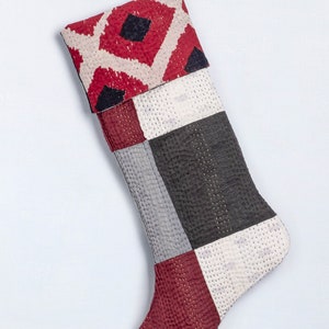 May include: A red, white and black patchwork Christmas stocking with a geometric pattern on the cuff.