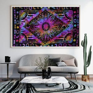 May include: A framed tapestry with a vibrant sun and celestial design. The artwork features a central sunburst motif in shades of purple, pink, and yellow, surrounded by moons and stars on a black background. The tapestry is displayed above a gray sofa.