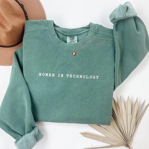 May include: A green sweatshirt with the text "Women in Technology" embroidered on the front.