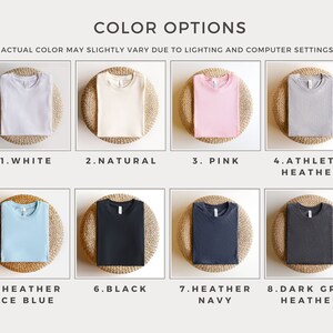 May include: Eight different color options for a t-shirt. The colors are white, natural, pink, athletic heather, heather ice blue, black, heather navy, and dark grey heather.