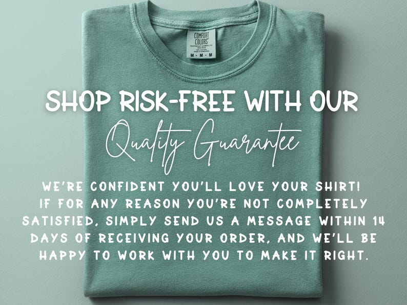 May include: A sage green t-shirt with the text "SHOP RISK-FREE WITH OUR Quality Guarantee". The shirt is folded neatly, with a tag visible at the collar. The text promises satisfaction.