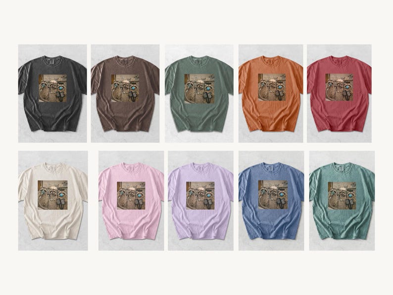 May include: A collection of ten short-sleeved t-shirts in various colors, including black, brown, green, orange, and pink. Each shirt features a graphic print of raccoons on motorcycles. The shirts are displayed on a white background.