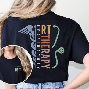 May include: Black t-shirt with a graphic design of a medical symbol, a stethoscope, and the text "RT THERAPY RESPIRATORY". The text is in a vertical orientation with each word in a different color.