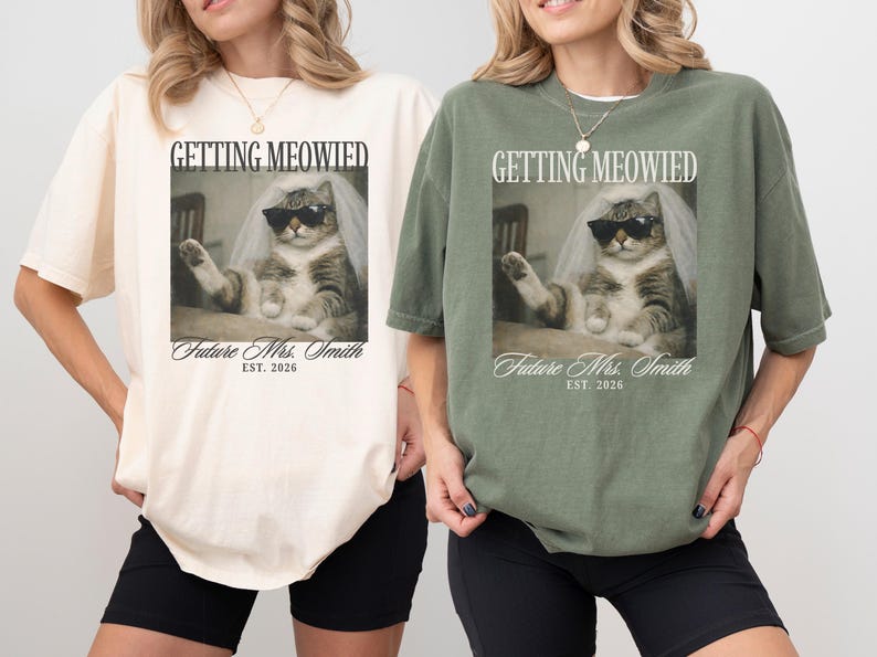 以下が含まれることがあります： クリーム色とオリーブグリーンの2枚のTシャツ。それぞれサングラスとベールをつけた猫が描かれています。「GETTING MEOWIED」と「Future Mrs. Smith EST. 2026」の文字が前面にプリントされています。