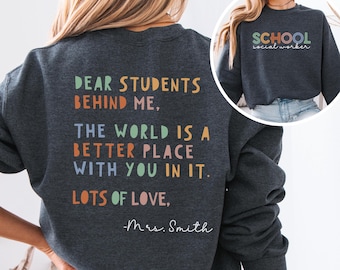 May include: A dark grey sweatshirt with a colourful message on the back that reads "Dear students behind me, the world is a better place with you in it. Lots of love, -Mrs. Smith". The front of the sweatshirt has the text "School social worker" in colourful letters.