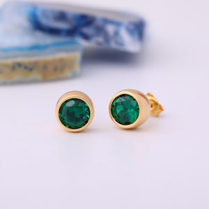 May include: A pair of gold-toned stud earrings with round green gemstones.