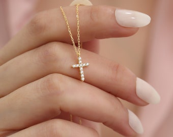 Puede incluir: Un collar de oro con un pequeño colgante de cruz engastado con diamantes.