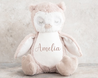 May include: A plush brown owl toy with white accents and closed eyes. The owl has a white patch on its chest with the name "Amelia" embroidered in pink.